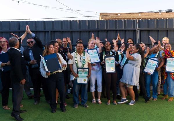 A group of students and faculty pose together for a photo while holding an award certificate.